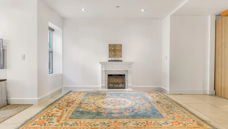 Blue rug with floral design in front of fireplace.