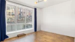 Empty room with wood floor and large window.