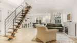 Modern living room with staircase and fireplace.