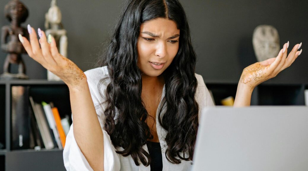 Woman looks confused at laptop screen.