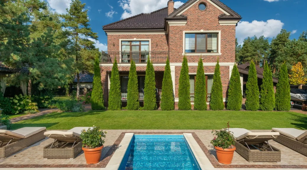 Brick house with a pool and lounge chairs.