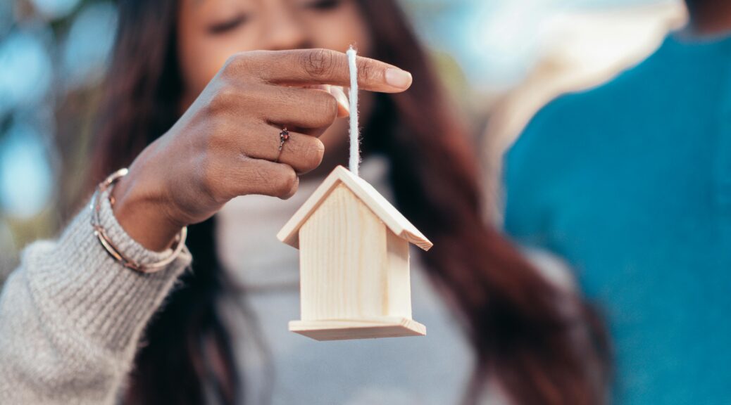 A woman holding a small wooden house.