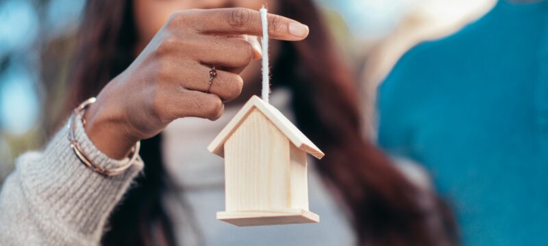 A woman holding a small wooden house.