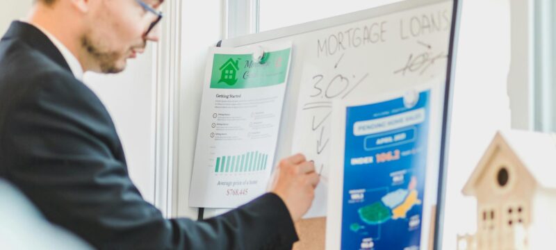 Man writing on whiteboard about mortgage loans.