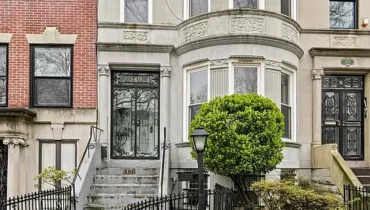 Gray and red row house with a black gate.