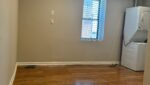 Empty room with wood floor and washer dryer.