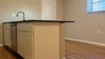 Kitchen island with white cabinets and wood floor.